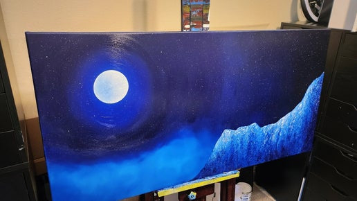 Lucid Dreaming Original Painting: A painting on an easel of a blue mountain, night sky, and a full moon.