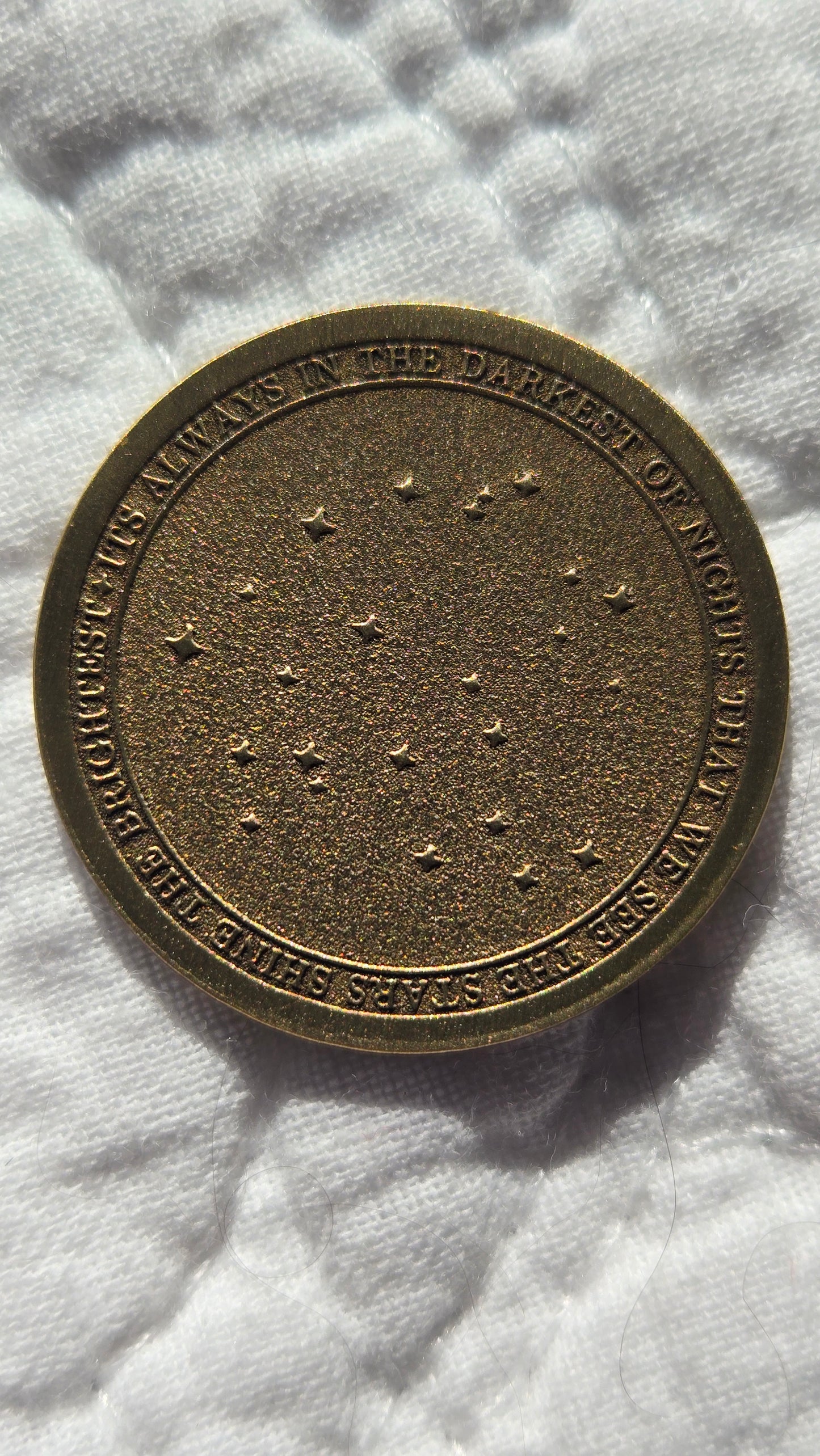 Bronze coin with engraved text and star patterns on a white fabric background