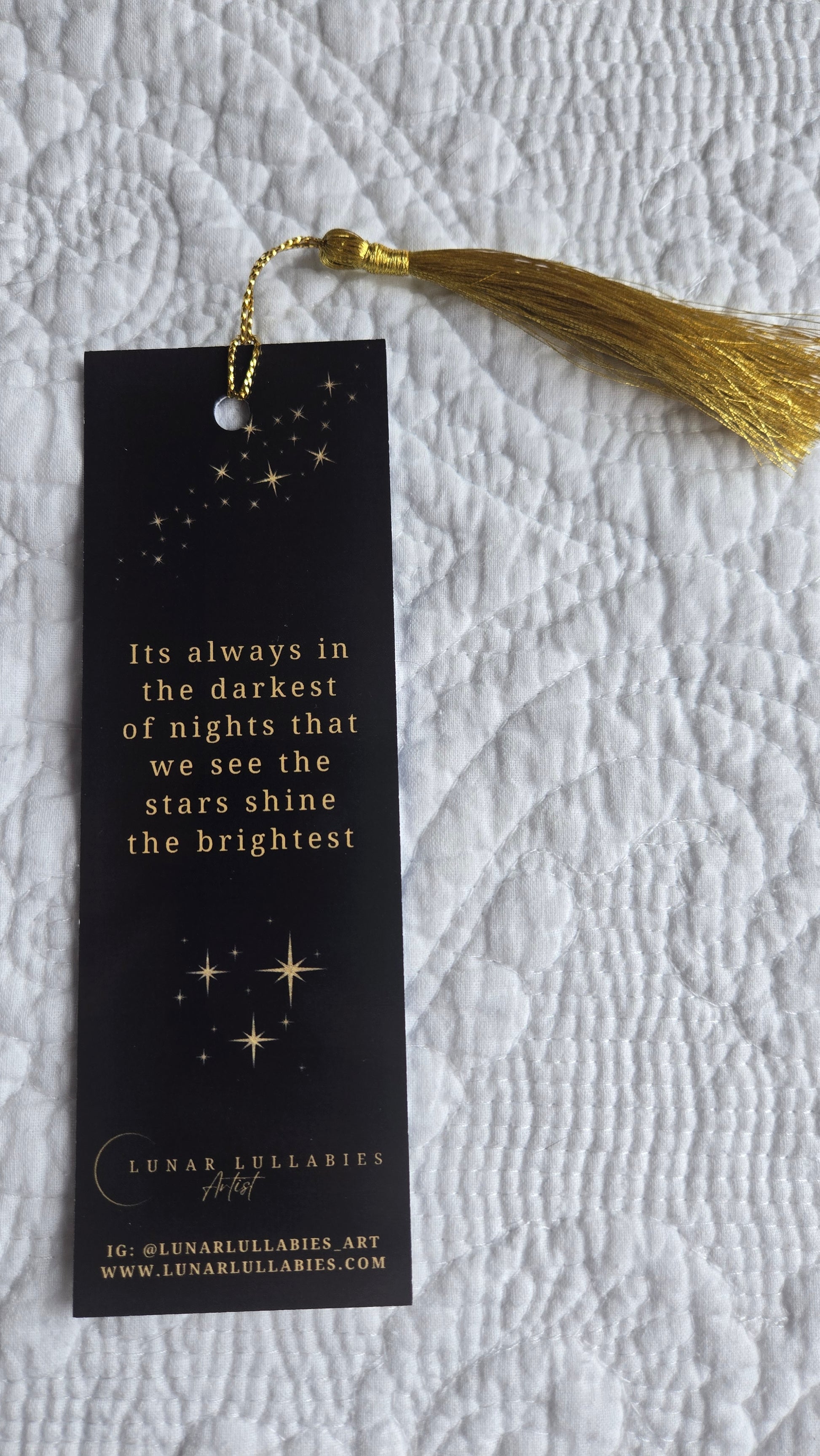 Black bookmark with gold tassel on textured fabric background