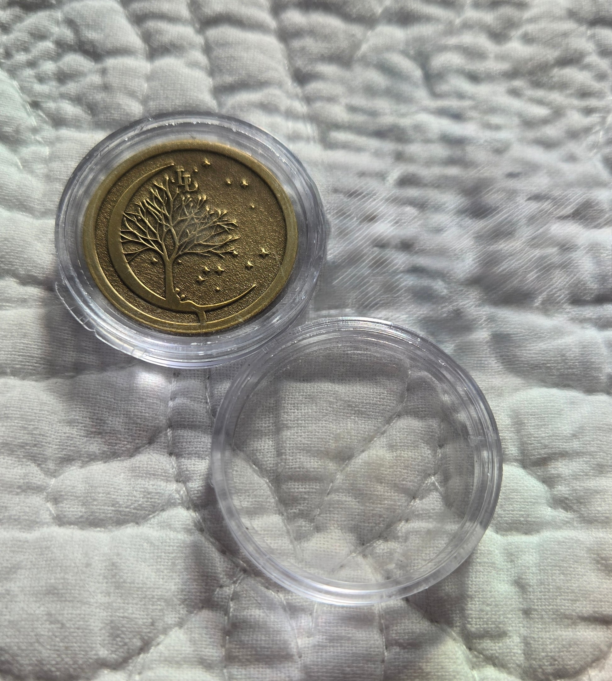 Bronze coin in a clear protective case on a textured fabric background