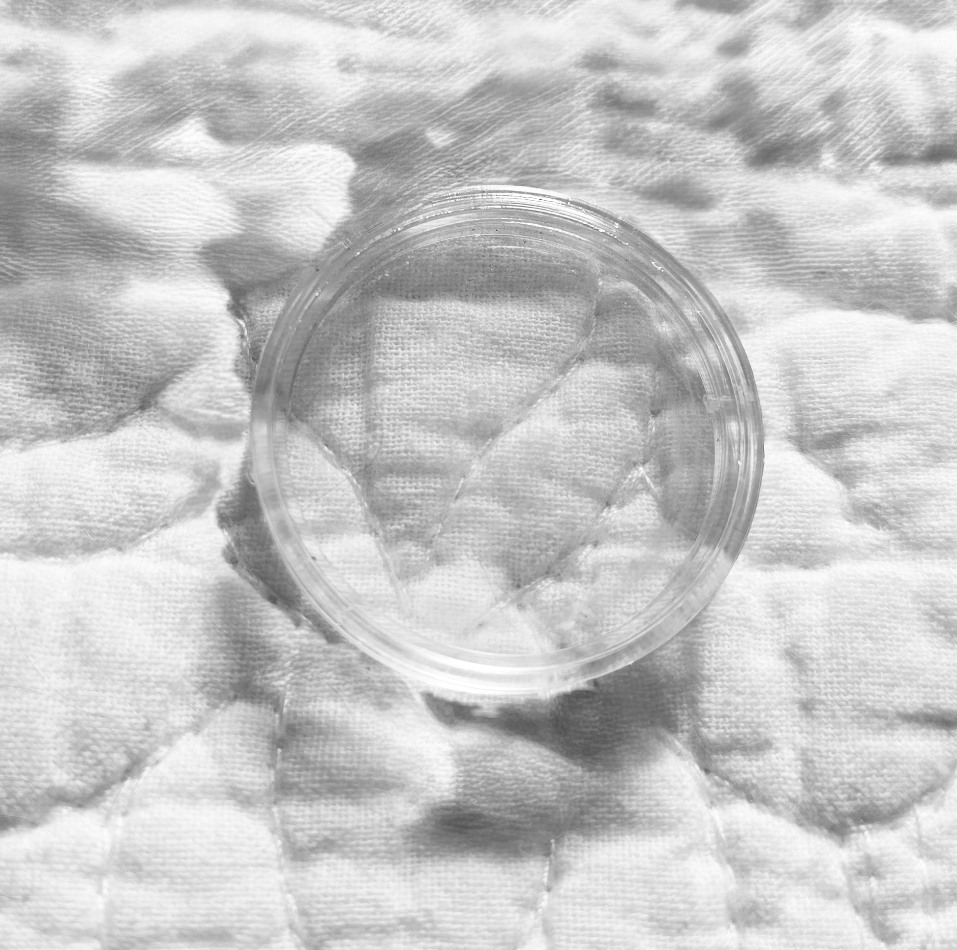 Clear plastic  coin container on a textured white fabric surface