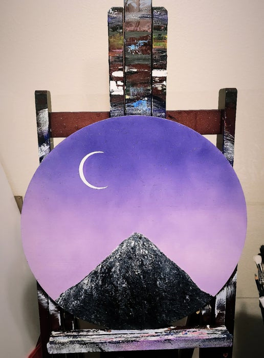 Crescent Signs Original Painting: Wood circle painting featuring a pink and purple sky, crescent moon, and a black and grey mountain peak.