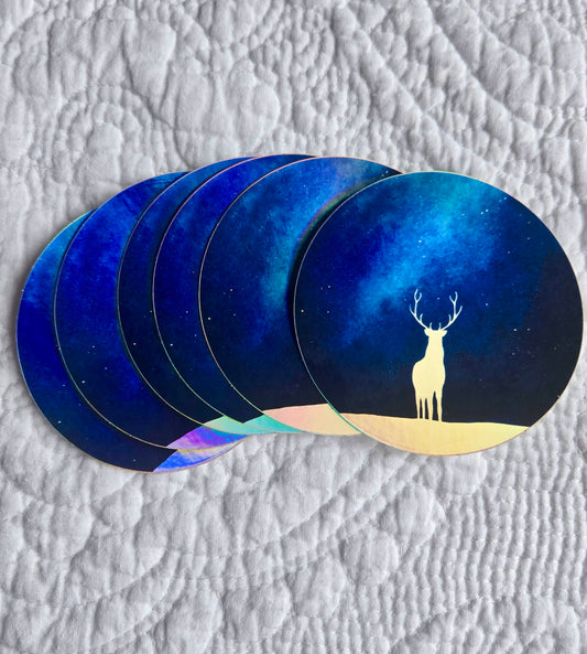 Six circular stickers with a deer design sitting on a textured surface