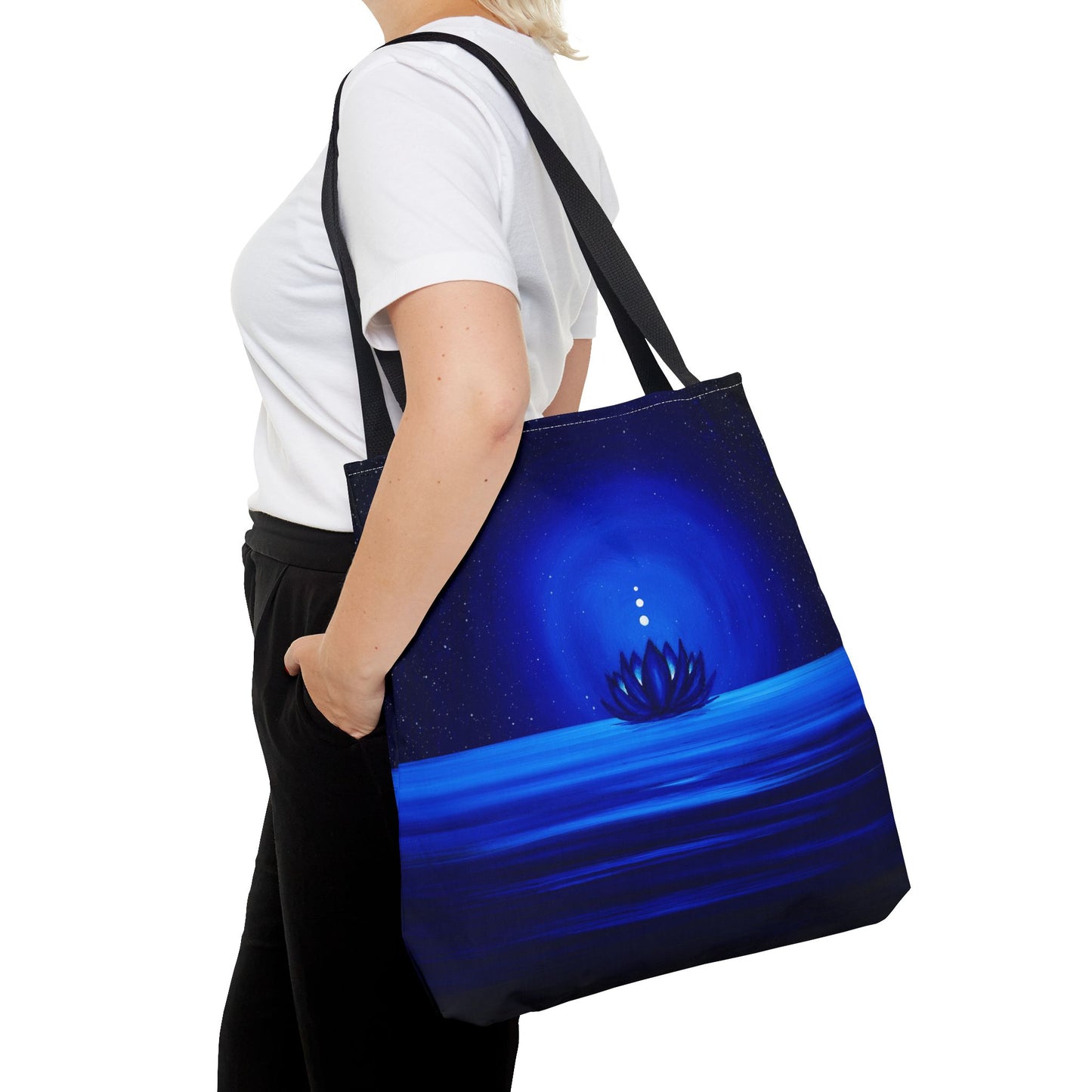 Person holding a blue tote bag with a celestial design.