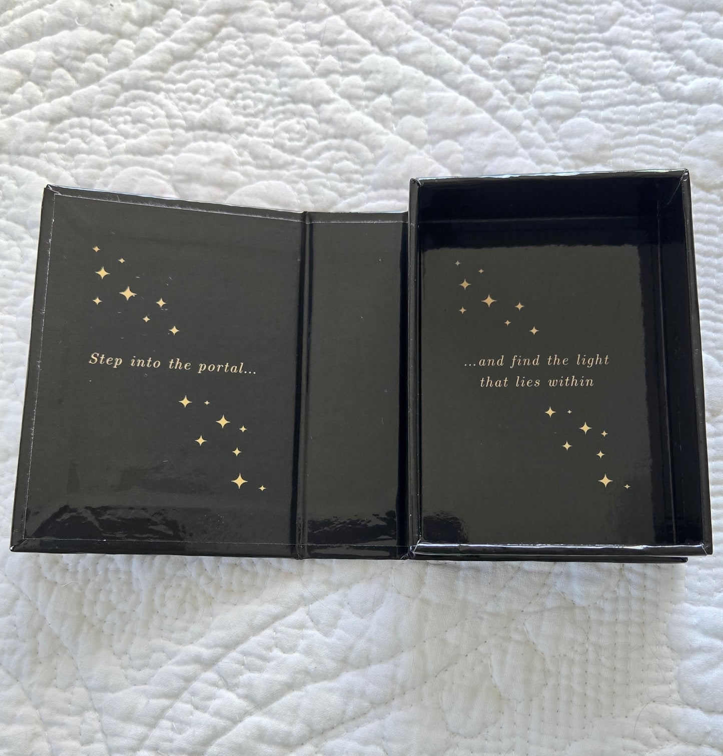 Black box with gold text and star illustrations on a textured white surface