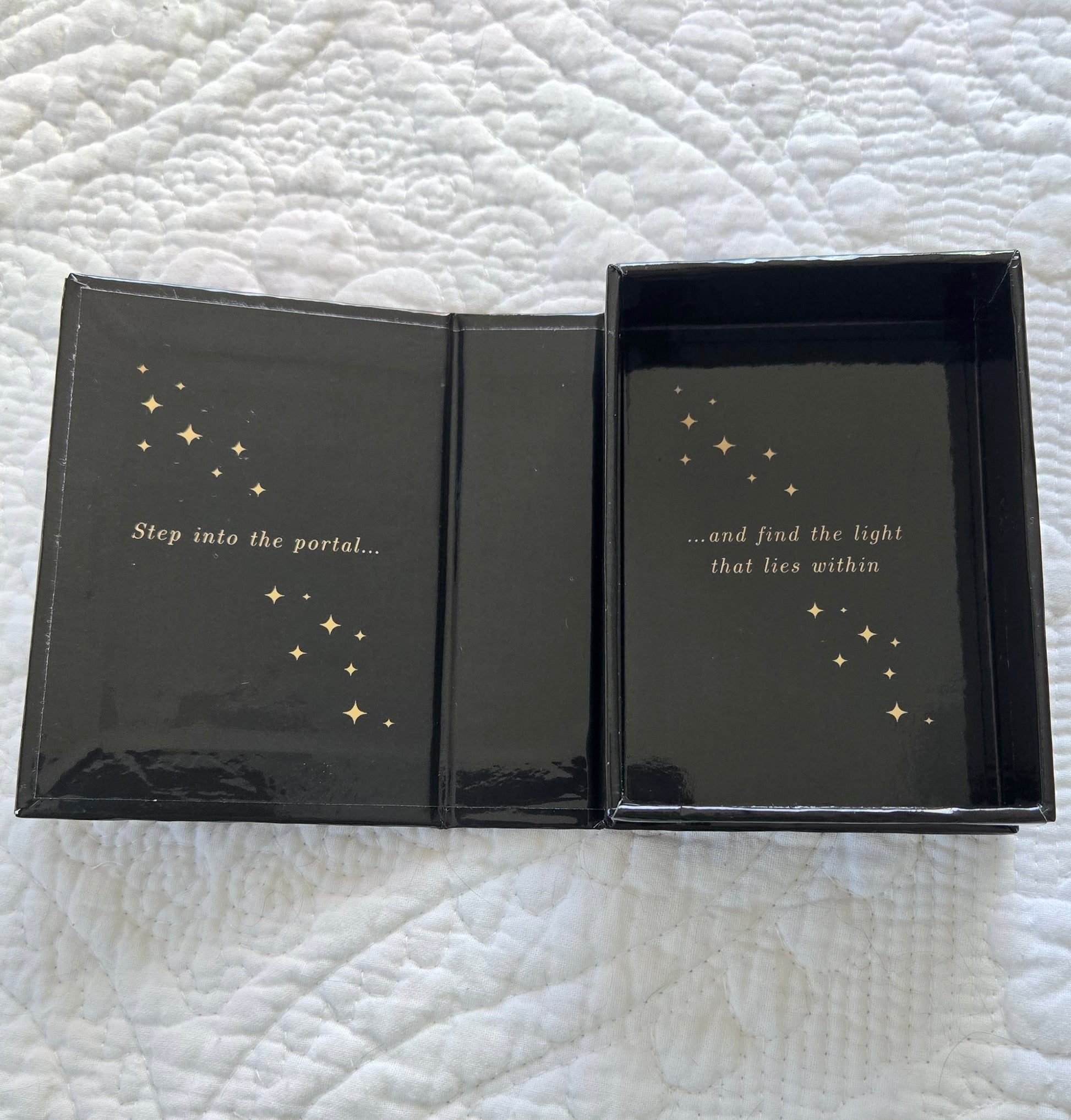 Black box with gold text and star illustrations on a textured white surface