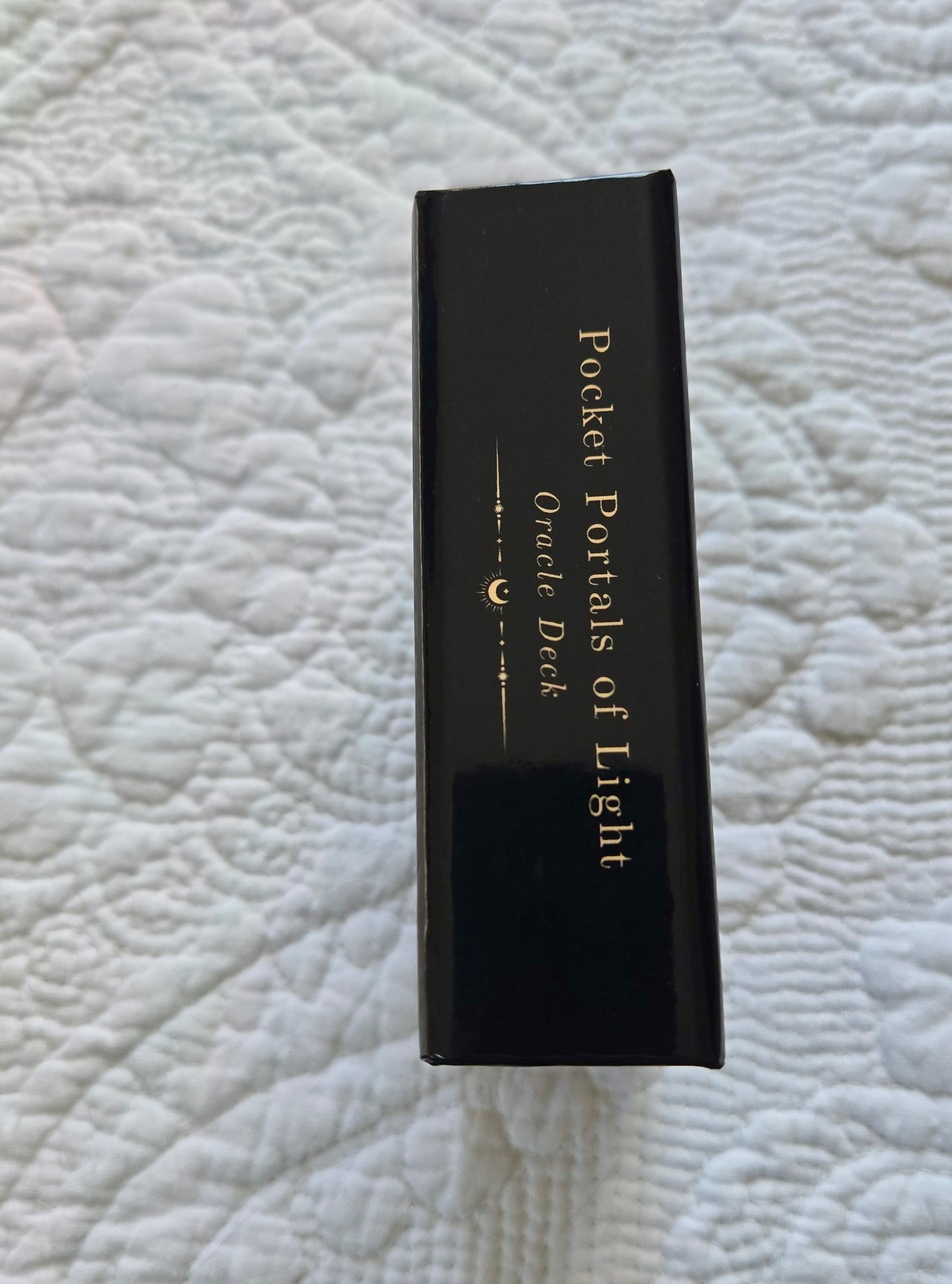Black box labeled 'Pocket Portals of Light Oracle Deck' on a textured white surface