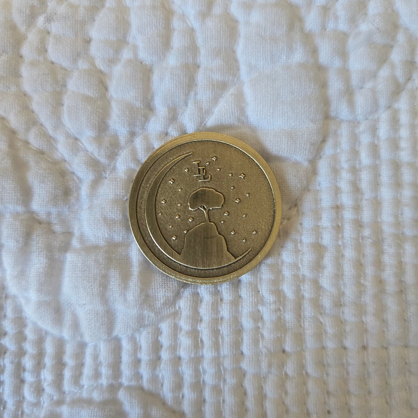Bronze coin with a design on a textured white fabric background