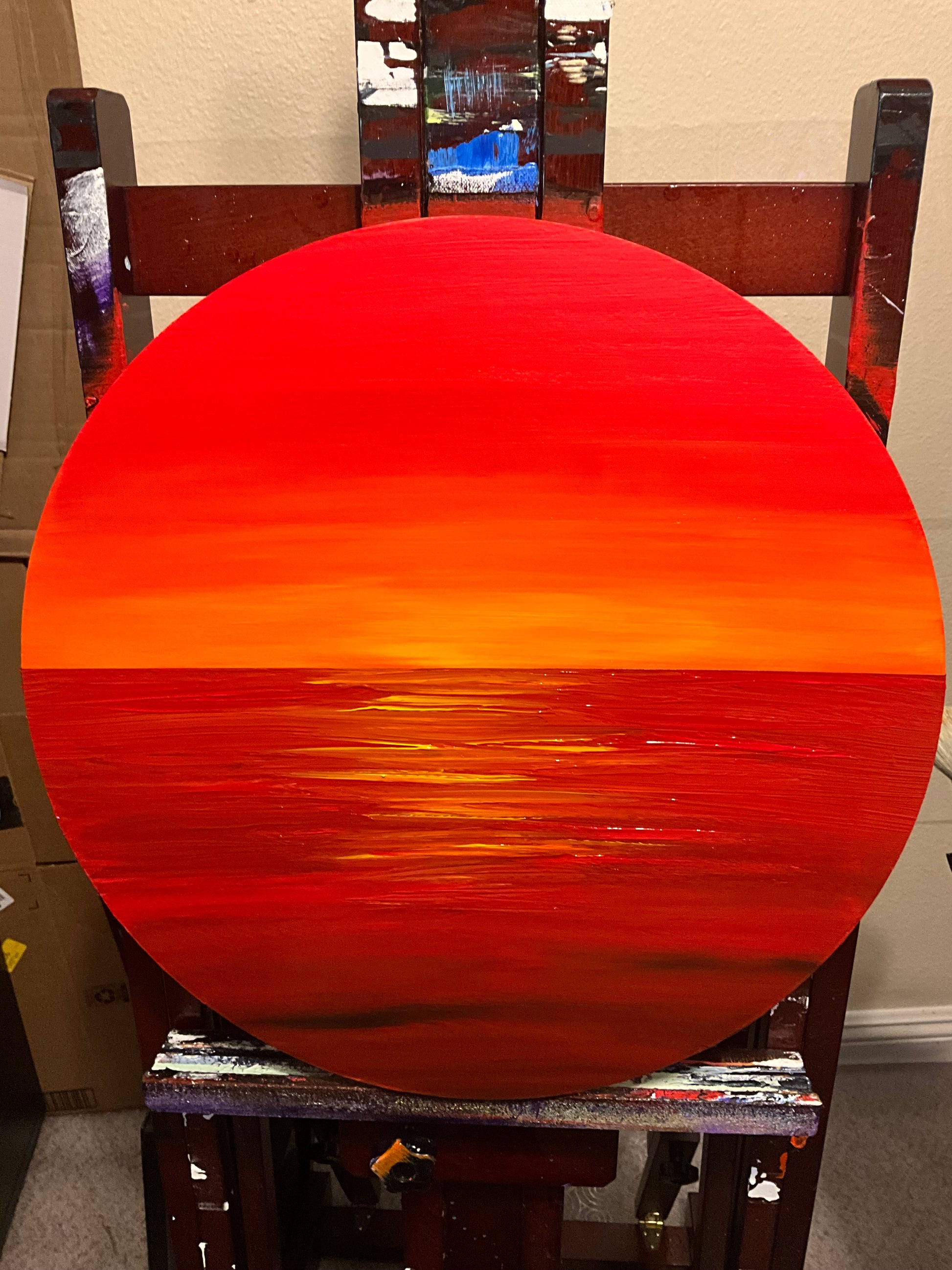 Wood panel painting on an easel of a red ocean and sky
