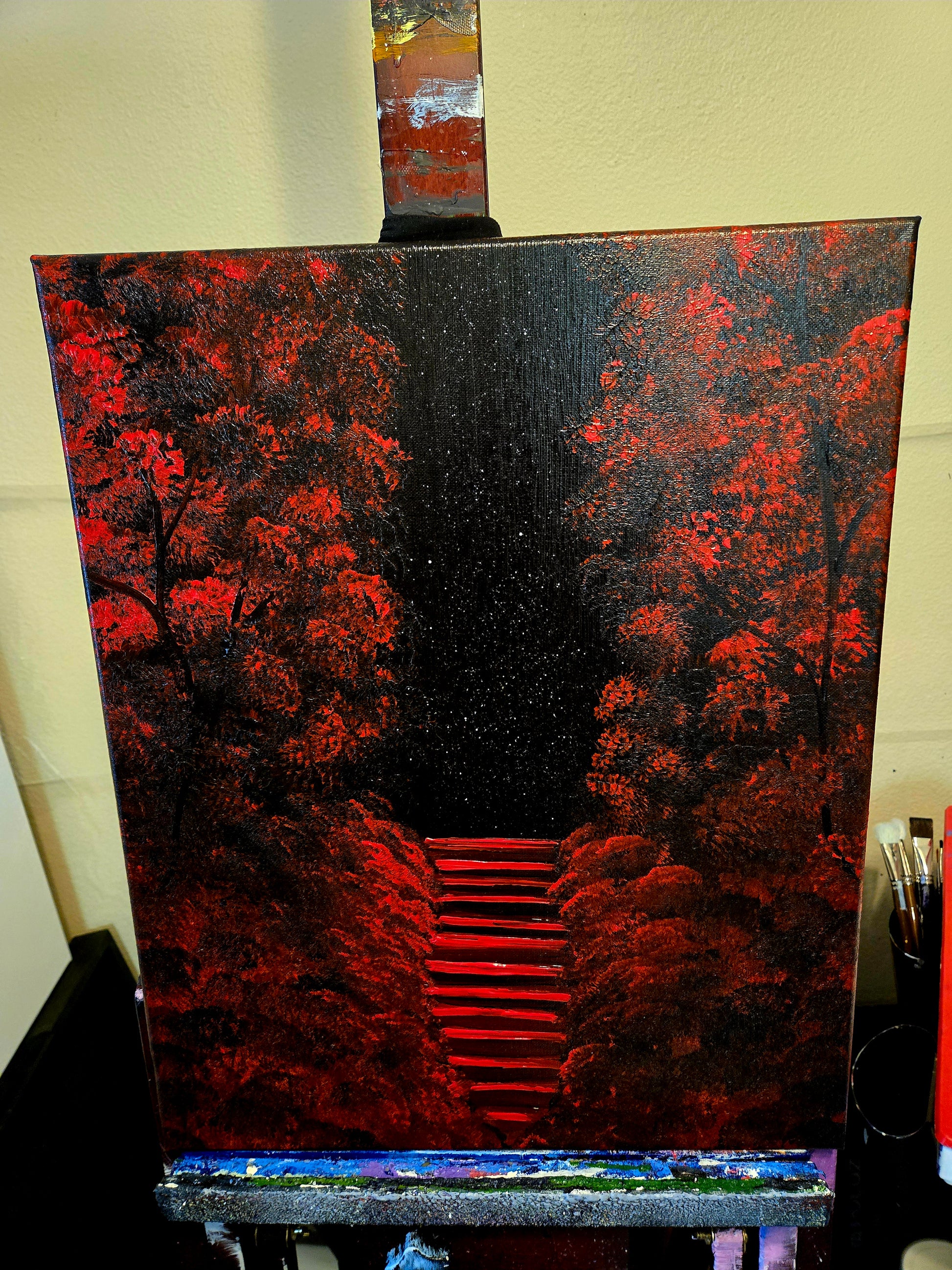 Painting on an easel of a red forest and red stars rising up through it