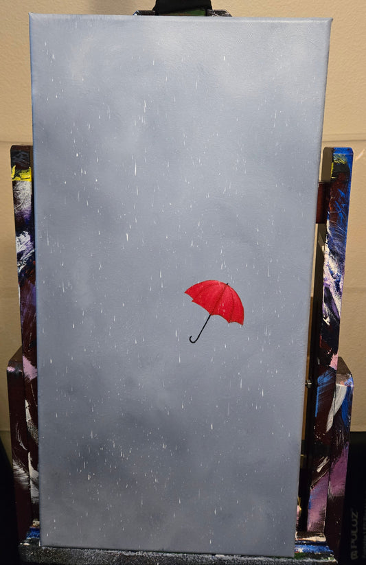 A painting on an easel of a red umbrella against a rainy grey cloudy storm