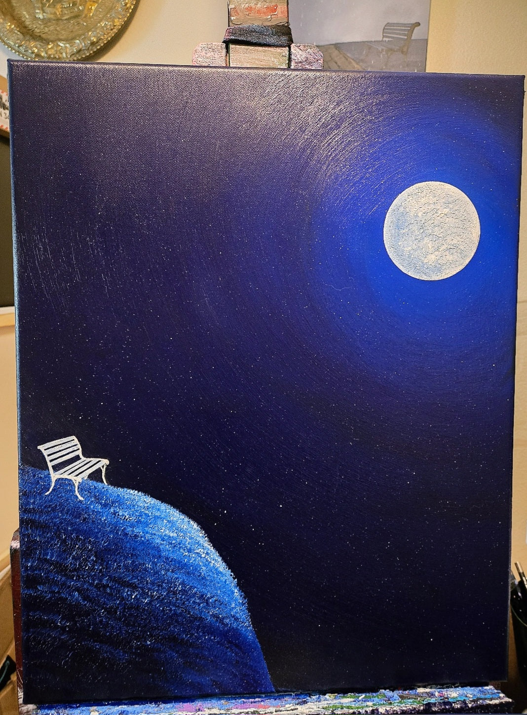 Painting of a bench on a moonlit night with a large moon in the sky.