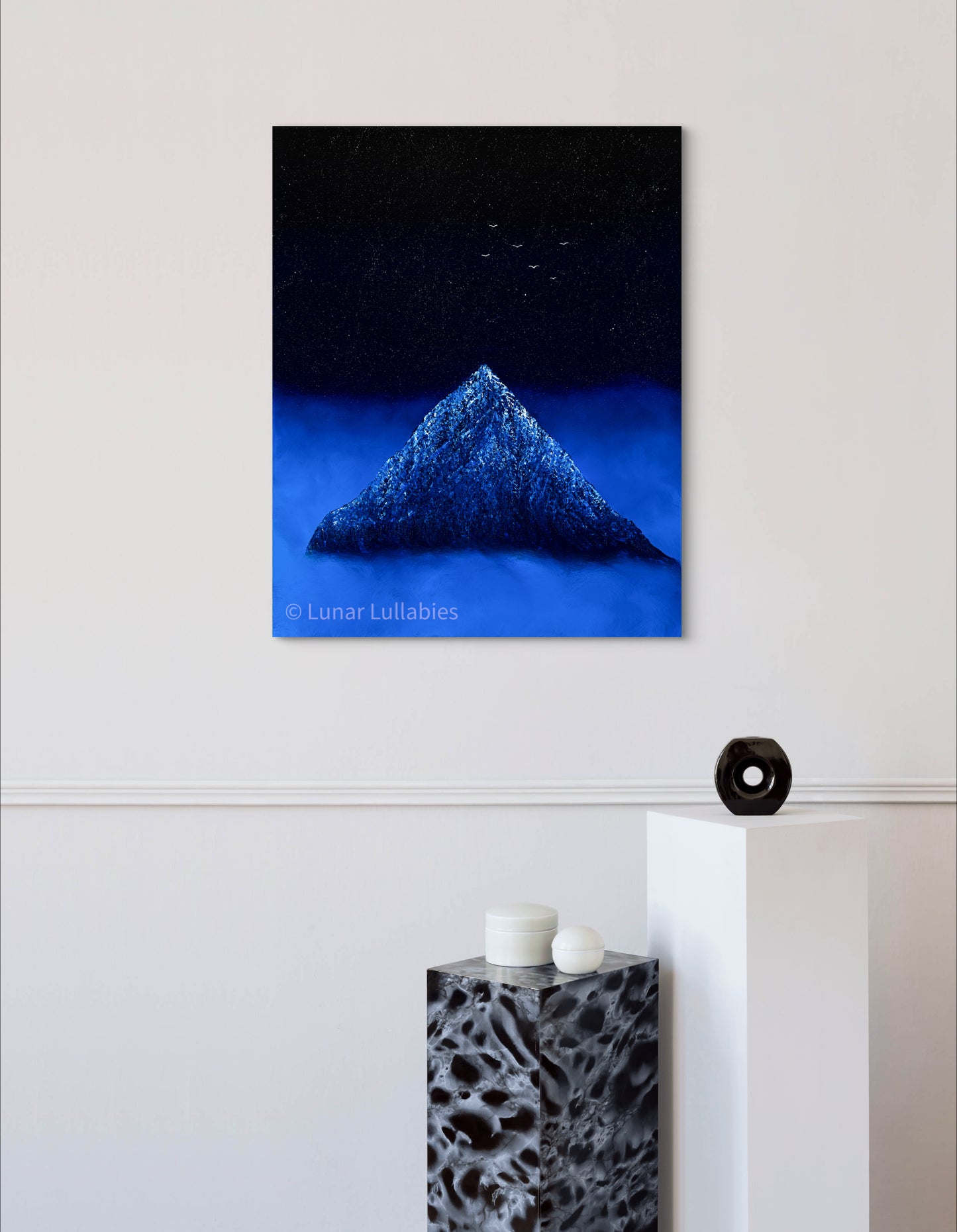 Mockup: Artwork of a mountain under a starry sky on a white wall.