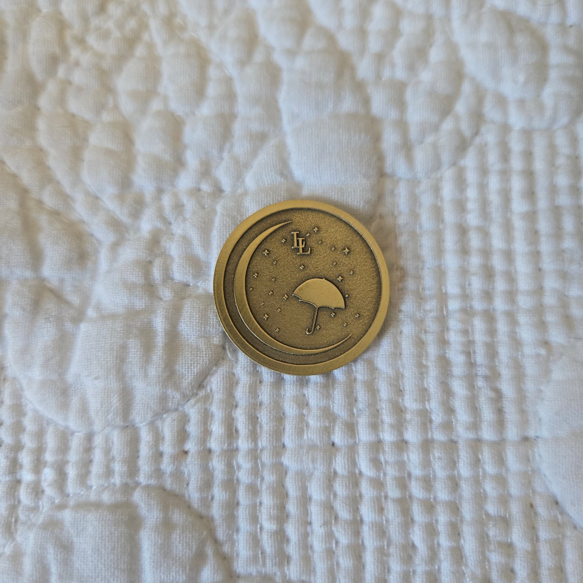 Bronze coin with embossed design on a textured white fabric background